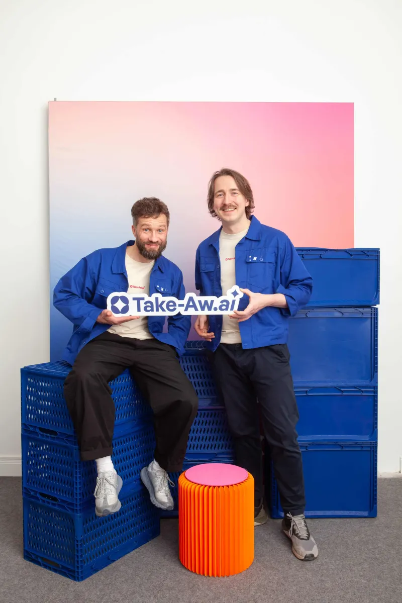 Rönke von der Heide and Michael Schieben holding a Take-Aw.ai logo sign